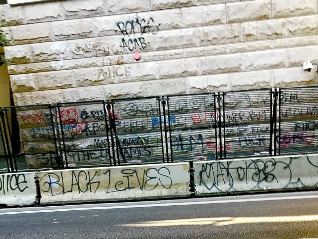 Metal barricades stand between graffitied barriers and the vandalized Multnomah County Courthouse in downtown Portland, Oregon on Monday, August, 10. 2020. (Photo courtesy of Zack)