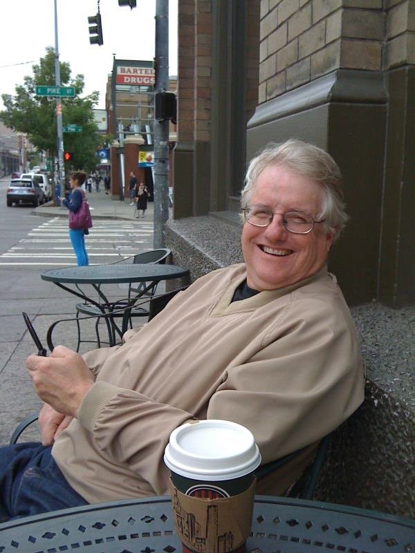 “Scott Strain sits happily with a cell phone and coffee at a coffee shop in Seattle, WA” Photo Courtesy of Mollie Brown