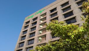 A neon sign on the Laney College Tower building lights up at dusk. The Tower houses the offices of administrators, counselors, and other Laney employees.