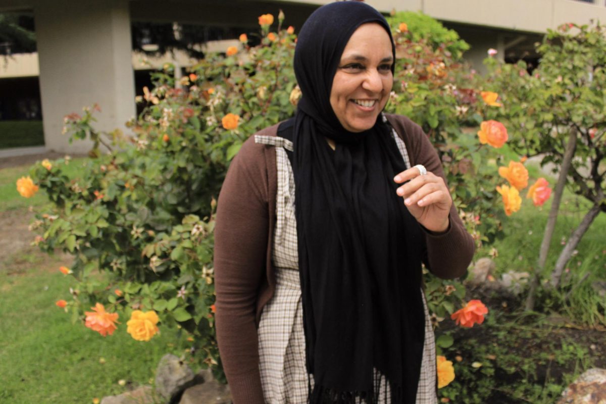 College of Alameda counselor and SALAAM co-founder Fathia Mohamed laughs in front of a yellow rose bush, Thursday Sept. 18, 2025. Alameda, CA.