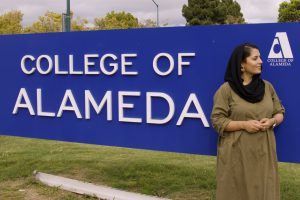 Mina Spasely, peer mentor for SALAAM learning community and nursing major at College of Alameda, poses in front of the sign for the college. SALAAM aims to uplift CoA students from Arab, Southwest Asian and North African diasporic communities.