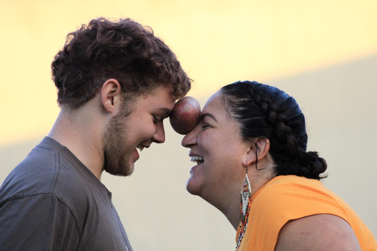 A pair competes in the Potato Dance contest, where two people hold a potato between their foreheads and dance around the arena at the NAHC Powwow at Merritt College in Oakland, CA., on September 27, 2025.