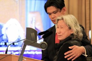 Anjru Jaezon de Leon, back, comforted his grandmother, Amelia Bulauan, during her emotional comments about the death of her son, Melvin Bulauan, at a Board of Supervisors committee hearing November 6.