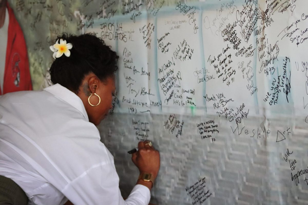 An attendee adds a message of support to a banner for John Beam's memorial at Laney College in Oakland, CA on Dec. 10, 2025.